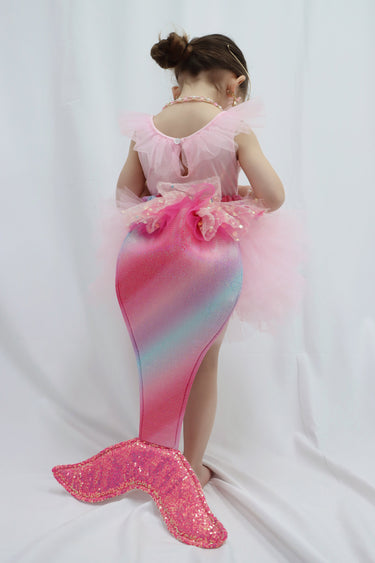 Child wearing a pink and blue mermaid tail costume on a white background